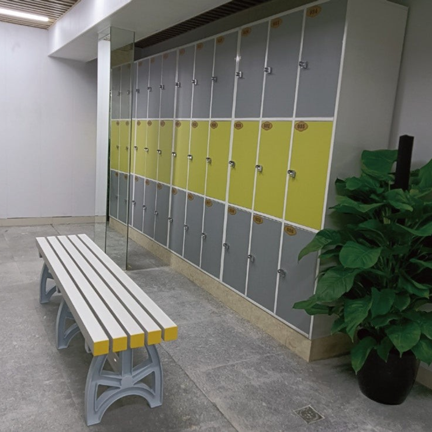 Tali Sport plastic changing room bench with white and yellow slats in a gym locker room setting.-3/7 