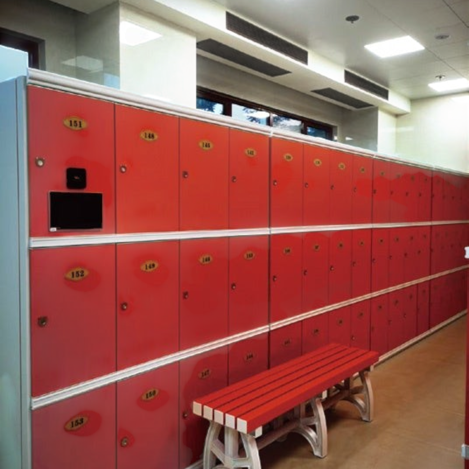 Tali Sport red plastic locker room bench with white legs placed in front of matching red lockers in a gym setting-5/7 