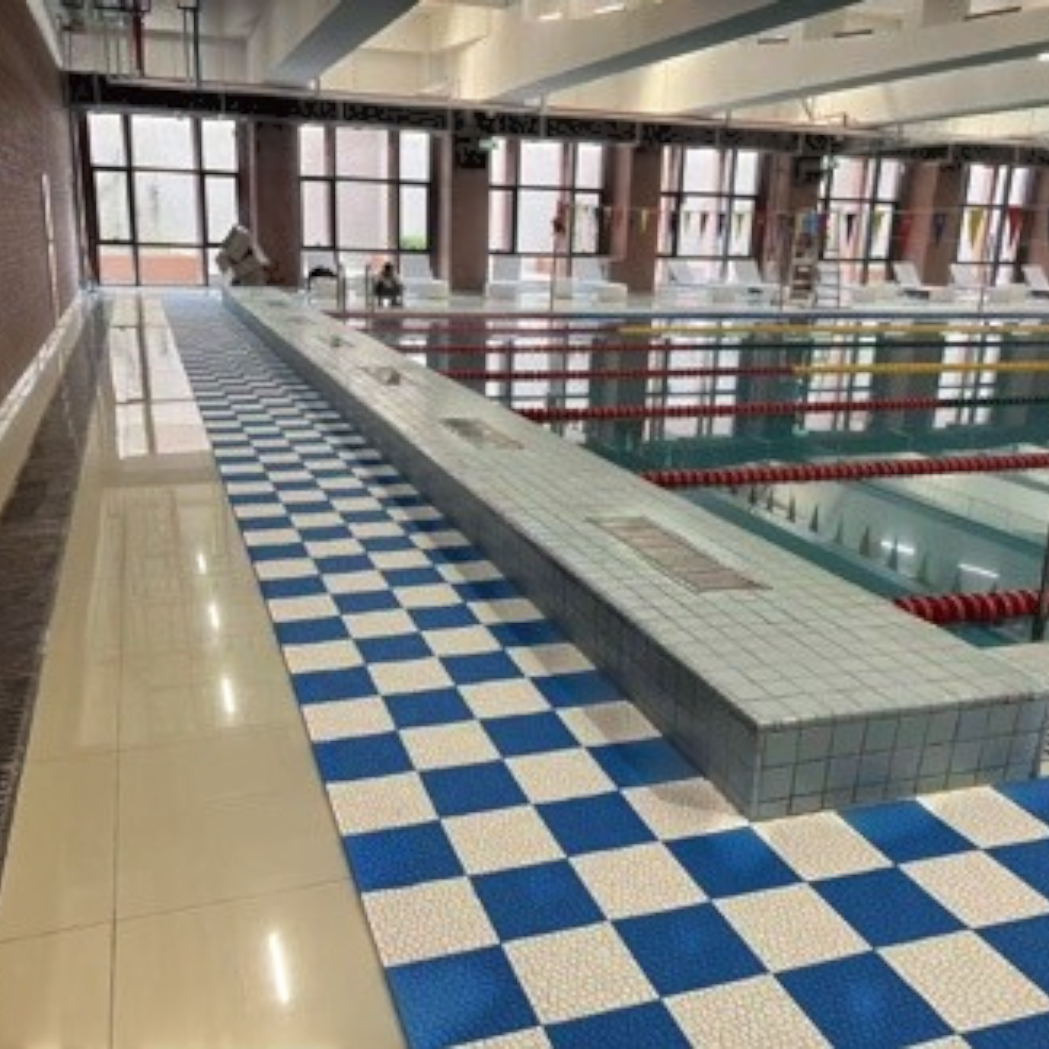 Tali Sport modular blue and white anti-slip PVC floor tiles installed around an indoor swimming pool deck-13/14 